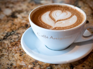 Café capuchino con espuma y patrón de corazón.