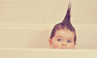 The child is bathing, his hair is standing