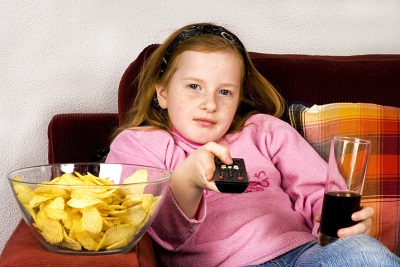 Ragazza di fronte alla TV con cola e patatine