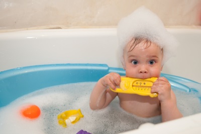 De jongen baadt in een bad met een thermometer voor water