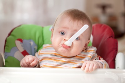 El niño tomó una cuchara en su boca al alimentarse.