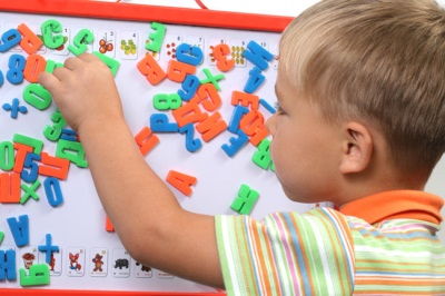 Niño y tablero magnético con letras.