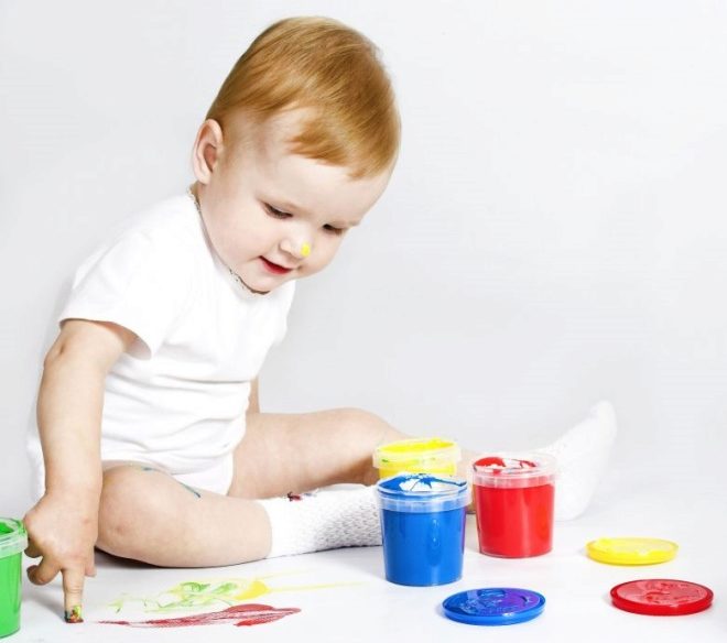 Un niño en 1 año dibuja con pinturas de dedos.